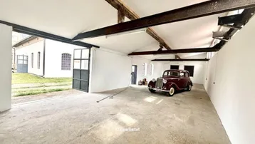 Geräumige Garage oder Werkstatt mit hohen Decken, freiliegenden Balken und Betonboden, ideal für Fahrzeuge.