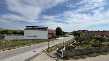 Weitblick über die ländliche Umgebung mit Wohnhäusern und Feldern unter weitem Himmel und Wolkenformationen.