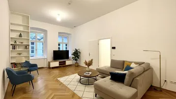 Helles Wohnzimmer mit modernem Mobiliar, Fischgrätparkett und hohen Decken.