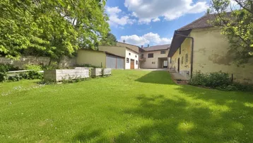 Großer Rasenbereich vor einem Gebäudekomplex mit mehreren Gebäuden unter blauem Himmel.