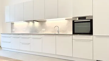 Moderne Einbauküche in Weiß mit integriertem Backofen und viel Stauraum.