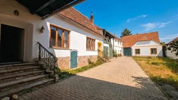 Traditionelles Gebäude mit gepflastertem Innenhof und mehreren Eingängen unter blauem Himmel.