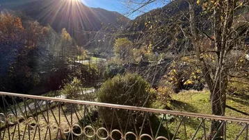 Sonniger Balkon mit Terrakottafliesen und weitem Blick auf die Berge und das Tal.