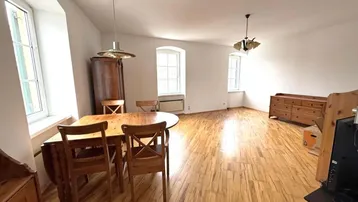 Helles Wohn- und Esszimmer mit Holzboden, traditionellen Möbeln und großen Fenstern.