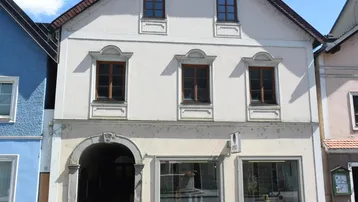 Historisches Gebäude mit traditioneller Fassade und Geschäftsräumen im Erdgeschoss.