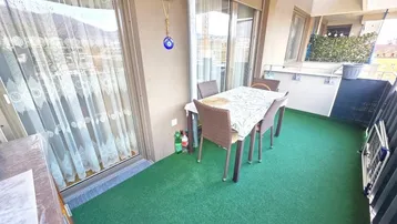 Gemütlicher Balkon mit Kunstrasen, Esstisch und Stühlen sowie Bergblick.