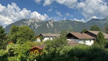 Panoramablick auf die umliegende Berglandschaft mit traditionellen Häusern und üppiger Vegetation.