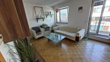 Helles Wohnzimmer mit Parkettboden, bequemen Möbeln und Zugang zu einem Balkon.