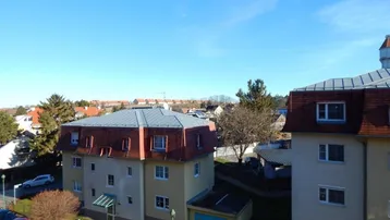 Weitläufiger Blick über Dächer und umliegende Gebäude an einem sonnigen Tag.
