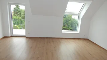 Helles Zimmer mit Laminatboden, großen Fenstern und Zugang zu einem Balkon.