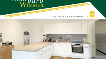 Moderne Küche mit weißen Schränken, heller Arbeitsplatte und Holzboden, gut ausgestattet.
