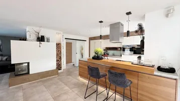 Offene Küche mit Kochinsel, Barhockern und einem modernen Kamin, der Wärme und Atmosphäre spendet.