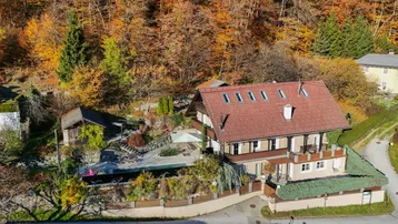 Luftaufnahme des Anwesens mit Haus, Poolbereich und umliegendem Herbstwald.