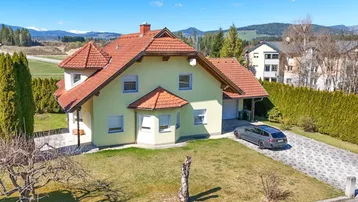Freistehendes Einfamilienhaus mit gepflegtem Garten, Auffahrt und Bergblick in ländlicher Umgebung.