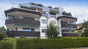 Mehrstöckiges Wohngebäude mit mehreren Balkonen und begrünten Dächern in moderner Architektur.