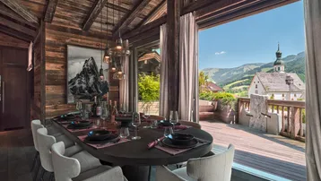 Geräumiger Essbereich mit Holzbalken, Bergblick und Zugang zur Terrasse durch große Fenster.
