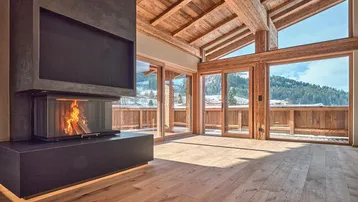 Helles Wohnzimmer mit modernem Kamin, Holzbalkendecke und großen Fenstern mit Bergblick.