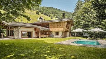 Luxuriöses Chalet mit großem Garten, Außenpool und Bergblick in alpiner Umgebung.