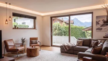 Helles Wohnzimmer mit gemütlicher Sitzecke, Holzboden und beeindruckendem Bergblick.