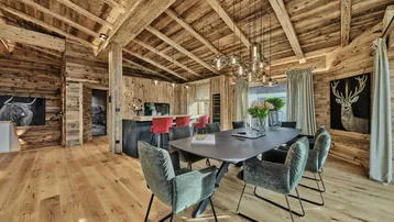 Geräumiger offener Wohn- und Essbereich mit Holzbalkendecke und moderner Küche im Chalet-Stil.
