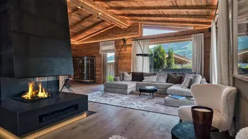 Modernes Wohnzimmer im Chalet-Stil mit großem Kamin, Holzbalkendecke und Panoramablick auf die Berge.