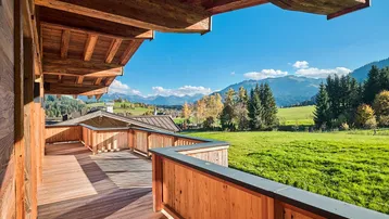 Geräumiger Holzbalkon mit atemberaubendem Blick auf die Berge und grüne Landschaft.