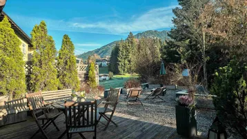 Geräumige Holzterrasse mit Sitzgelegenheiten und weitem Blick auf die umliegende Berglandschaft.