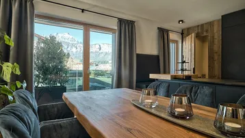 Moderner Essbereich mit Holztisch, bequemen Stühlen und Panoramablick auf die Berge.
