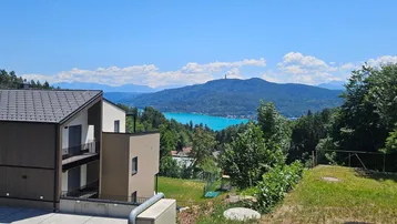 Modernes Gebäude in Hanglage mit weitem Blick auf den See und die umliegenden Berge.