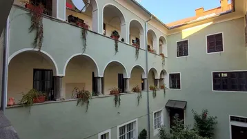 Blick in den Innenhof eines Altbaus mit Arkadengängen und begrünten Balkonen.