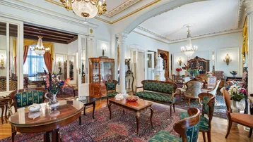 Großzügiger Salon mit eleganten Möbeln, Kronleuchtern und Parkettboden in einer aristokratischen Villa.