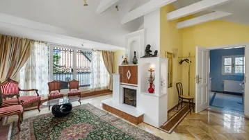 Gemütlicher Wohnbereich mit Kamin, Holzbalken und Zugang zu einem Balkon.