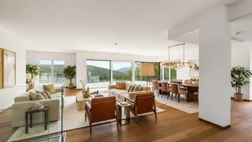 Helles, offenes Wohn- und Esszimmer mit Holzboden und Panoramablick auf die grüne Landschaft.