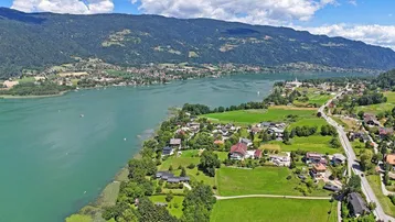 Weitläufige Luftaufnahme der Seenlandschaft mit umliegenden Dörfern und grünen Bergen.
