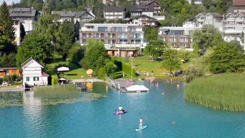 Luftaufnahme eines modernen Apartmentkomplexes am Seeufer mit Badestrand und umliegender Natur.