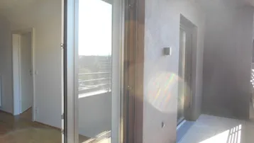 Balkon mit Fliesenboden und Blick auf die Umgebung, zugänglich durch eine große Glastür.