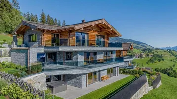 Luxuriöses Chalet mit moderner Architektur, Holz- und Steinfassade, Glasbalkonen und atemberaubendem Bergblick.