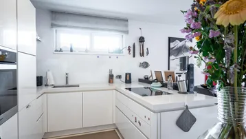 Helle, moderne Einbauküche in Weiß mit Induktionskochfeld und Fenster für viel Tageslicht.
