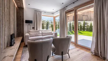 Helles Wohnzimmer mit Holzwand, bequemen Sitzmöbeln und Zugang zum Garten.