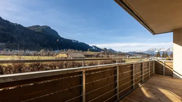 Geräumiger Balkon mit Holzboden und weitem Blick auf die umliegende Berglandschaft.