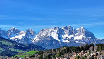 Panoramablick auf schneebedeckte Berge und ein malerisches Dorf in den Alpen.