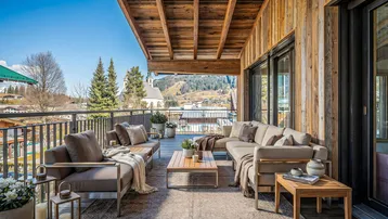 Geräumige Terrasse mit bequemen Loungemöbeln, Holzwänden und herrlichem Bergblick.