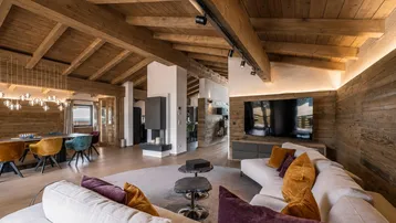 Geräumiger Wohn- und Essbereich mit Holzbalkendecke, modernem Kamin und stilvollen Möbeln.