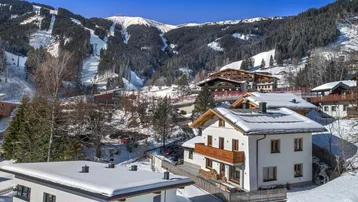 Haus in verschneiter Berglandschaft mit Blick auf die Skipisten und umliegende Chalets.