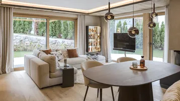 Helles, modernes Wohn-Esszimmer mit Holzboden, großen Fenstern und Zugang zum Garten.