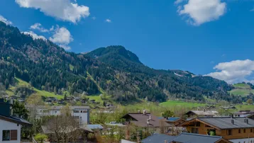Panoramablick auf die umliegende Berglandschaft mit traditionellen Häusern unter blauem Himmel.