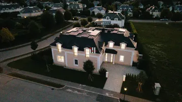 Luftaufnahme eines modernen Hauses mit Solaranlage, gepflegtem Garten und Bergblick in einer ruhigen Wohnsiedlung.