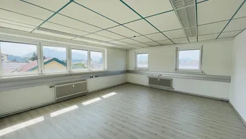 Heller Büroraum mit großen Fenstern, die einen Blick auf die Berge und die Umgebung bieten.