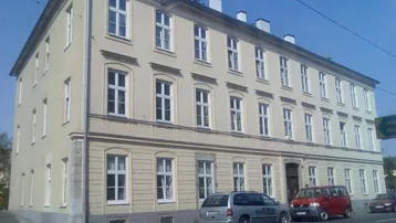 Klassisches Mehrfamilienhaus mit beiger Fassade und vielen Fenstern an einer Straße gelegen.