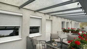 Überdachter Balkon mit Sitzgelegenheiten und Blumenkästen, ideal für entspannte Stunden im Freien.